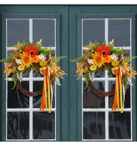Close-up of autumn harvest wreath with sunflowers and pumpkins on a dark window