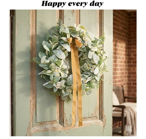 Artistic detail of a floral wreath with white daisies and yellow ribbon on a green door