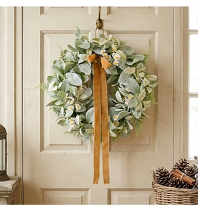 Close-up of artificial garland with velvet leaves, white daisies and amber velvet ribbon
