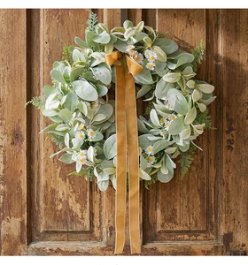 Detailed texture of eucalyptus wreath with white daisies and golden velvet ribbon on door