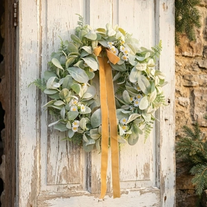 Rustic wreath with eucalyptus leaves, white daisies and golden velvet ribbons on vintage door