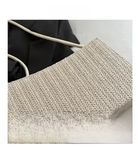 Macro detail of beige woven shoulder bag showing fine herringbone texture and slim strap