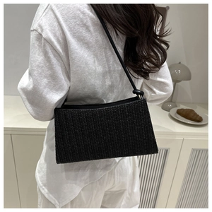 Detail of black woven shoulder bag with intricate texture and minimalist knotted strap