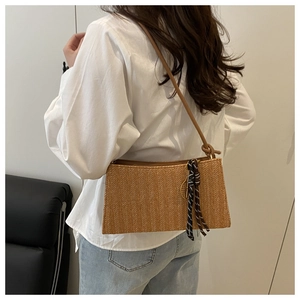 Detail of hand-woven straw shoulder bag with V-shaped texture and striped silk scarf