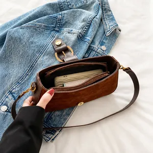 Detailed view of dark brown suede shoulder bag interior with magnetic clasp and zipper