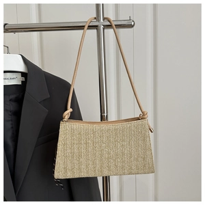 Detail of beige straw bag with herringbone weave and adjustable leather strap