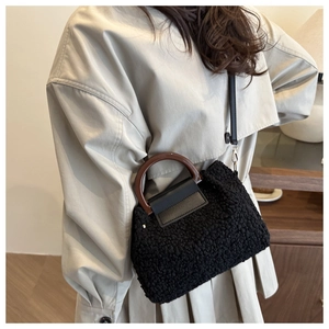 Detail der schwarzen Teddy-Plüschtasche mit dunkelbraunem Holzgriff und Leder-Klappe