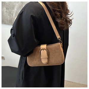 Détail du sac sous le bras en daim beige avec grande boucle en métal sur modèle