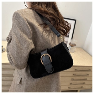Macro detail of black vintage underarm bag with gold horseshoe buckle on wool blazer