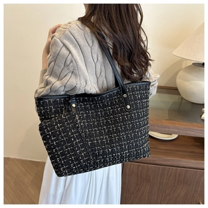 Détail du sac cabas en tweed avec texture tissée noire et dorée et anses en cuir