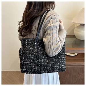 Gros plan d'un sac cabas en tweed noir et doré avec pochette sur pull beige