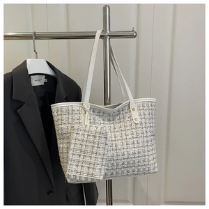Détail d'un sac cabas en tweed et sa pochette assortie sur un présentoir minimaliste moderne