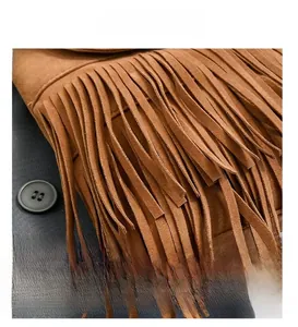 Detailed macro view of a brown suede bucket bag featuring long fringe and metal ring hardware
