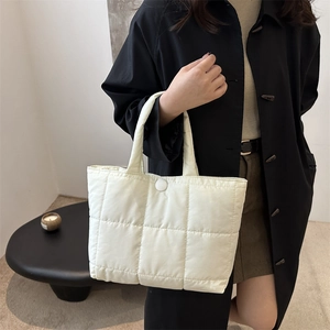 Close-up of quilted cream tote bag showing soft nylon texture and snap button closure