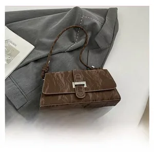 Vue détaillée du sac en cuir marron plissé à côté d'un smartphone pour la taille