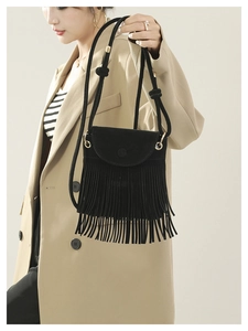 Detail of black matte suede bucket bag featuring long fringe tassels and drawstring strap