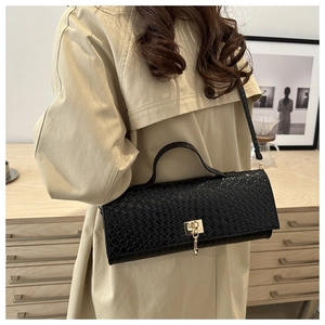 Close-up of black woven texture handbag featuring a gold lock and elegant fringe detail