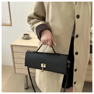 Close-up of black woven texture leather handbag with elegant gold metal square lock