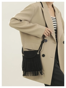 Detail of black suede bucket bag featuring triple-layered tassels and gold metal hardware
