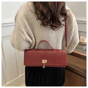 Detail view of woven texture burgundy shoulder bag with gold clasp on a model
