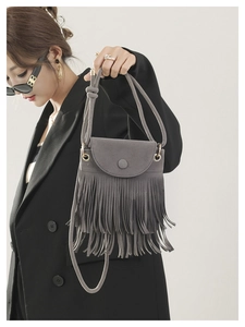 Detail view of dark grey suede crossbody bucket bag with long tassel and thin strap