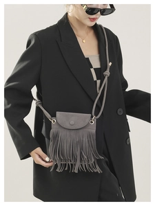 Detail view of a gray matte bucket bag featuring stylish long fringe and knotted rope strap