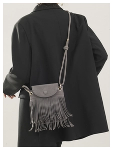 Detail of gray fringe bucket bag showing suede-like texture and tassel trim
