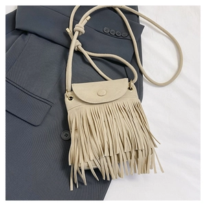 Close-up of beige fringe crossbody bucket bag with matte texture and bohemian tassels