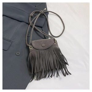 Detailed view of dark grey matte bucket bag with long tassels and gold metal eyelets