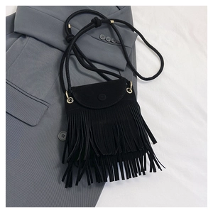 Close-up of black suede tassel bucket bag with snap button flap on a gray blazer