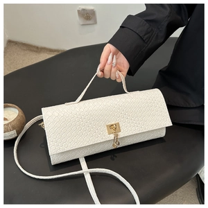 Close-up of white woven leather bag with gold buckle and chain on black surface