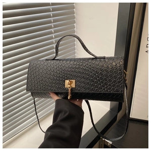 Close-up of black crocodile pattern faux leather texture and gold metal buckle lock
