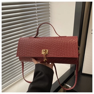 Detail of deep brick red woven texture and golden alloy lock on stylish handbag