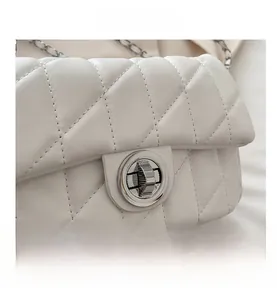 Gros plan sur la texture du cuir blanc matelassé et le fermoir rotatif argenté du sac
