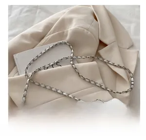 Détail du sac bandoulière blanc matelassé avec chaîne sur un blazer beige