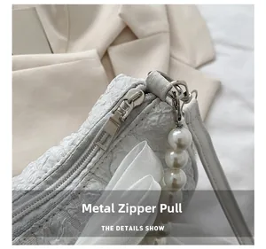 Detail of white bubble pleated bag featuring silver zipper and large pearl pendant