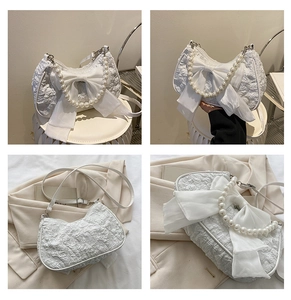 Detail of white pleated handbag with large bow, pearl chain and adjustable strap