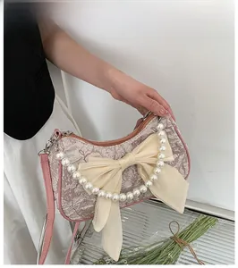 Close-up of pink pleated handbag with large satin bow and pearl handle detail