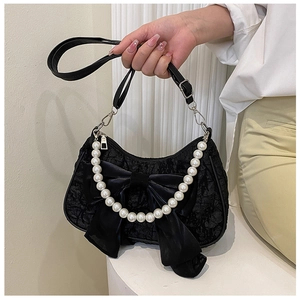 Close-up of black lace handbag with large satin bow and white faux pearl chain strap
