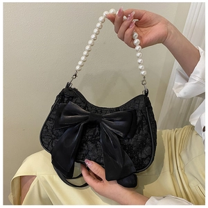 Detail of black pleated crescent bag featuring oversized silk bow and white pearl handle