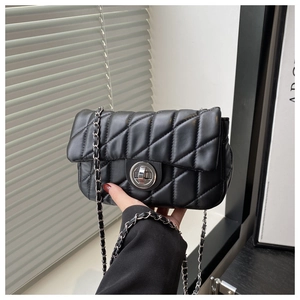 Détail du sac matelassé noir avec fermoir tournant argenté et bandoulière en chaîne