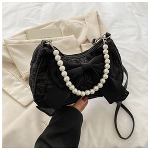 Close-up of black pleated handbag with oversized bow detail and elegant pearl handle