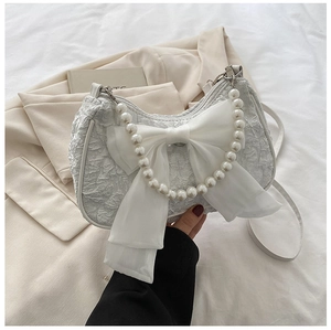 Detail of white pleated handbag featuring organza bow and elegant pearl handle