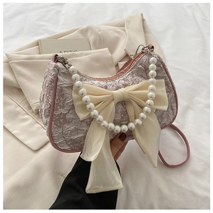 Close-up of pink embossed fabric bag with mesh bow and elegant pearl handle detail
