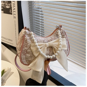 Detail of pearl handle and chiffon bow on a pleated pink floral jacquard handbag