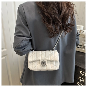 Sac à bandoulière matelassé blanc porté par un mannequin en veste de blazer grise