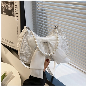 Detail of white pleated handbag featuring organza bow and elegant pearl handle strap