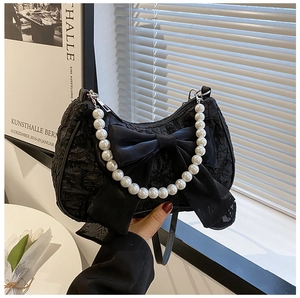 Detail of black pleated handbag featuring an oversized bow and elegant pearl handle