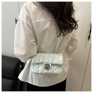 Détail d'un sac à chaîne matelassé vert menthe porté par un mannequin en extérieur