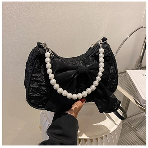 Detail of black pleated shoulder bag featuring oversized satin bow and large pearl handle